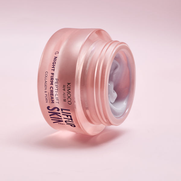 Otwarty różowy słoiczek kosmetyku Kimoco Lift-Up Skin Pepti-Lift Night Firm Cream z kolagenem i PDRN, z widoczną białą konsystencją kremu wewnątrz, na jasnoróżowym tle